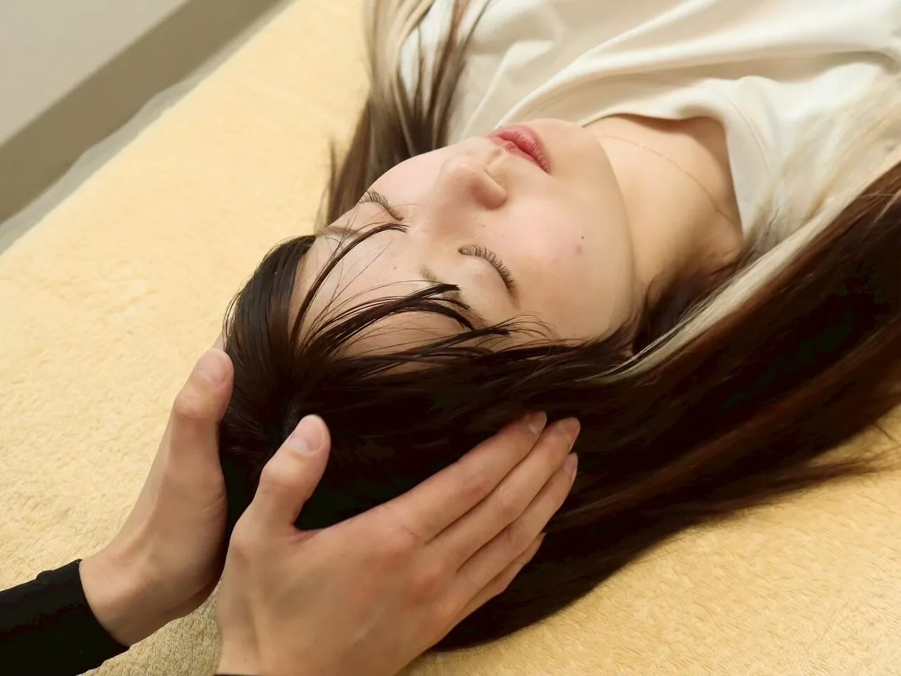 si'seの小顔矯正：仰向けのお客さまの頭部をやさしく包み込むように整える施術風景
